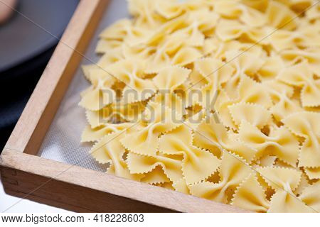 Raw Food Composition - Yellow Farfelle Pasta In A Basket.