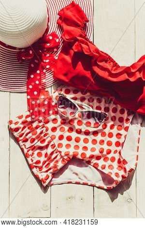 Feminine Red Retro Swimsuit, Hat And Beach Accessories On White Wooden Background. Flat Lay, Top Vie