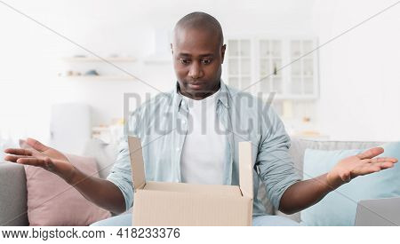Home Delivery. Shocked African American Man Spreading His Hands, Having Problem, Getting Wrong Order