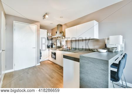Corner Cupboards And Table With Chairs Located In Light Kitchen Of Contemporary Flat