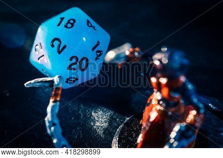 Close-up Of A Blue Twenty Sided Dice And A Role Playing Mini On A Dark Surface. Focused On The Dice 