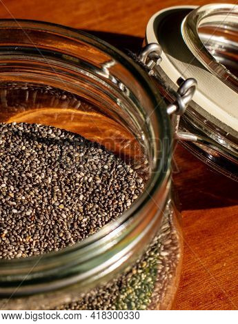 Close Up Of A Glass Wack Jar Filled With Chia Seeds On Red Wood Background