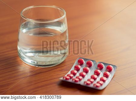 Medicines Or Tablets With A Glass Of Water On A Wooden Table For Sick Patient. Concept For Covid-19,