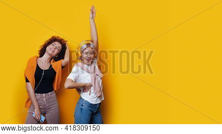 Cheering Curly Haired Sister Are Listening To Music On A Yellow Studio Wall With Free Space