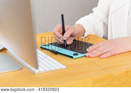 Close-up Of Female Hands Using Digital Graphics Tablet And Stylus While Working In Modern Office
