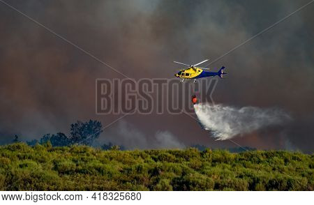 Helicopter With Bambi Bucket Throwing Water With Smoke In The Background