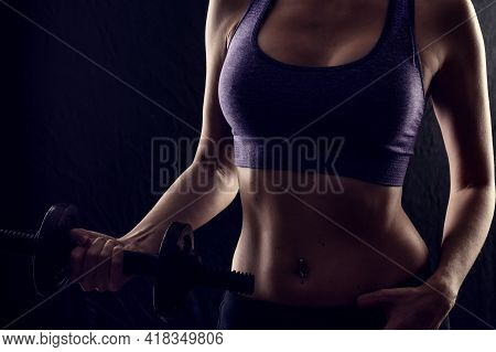 Slim Athletic Woman Holding Dumbbell In The Hand On Black