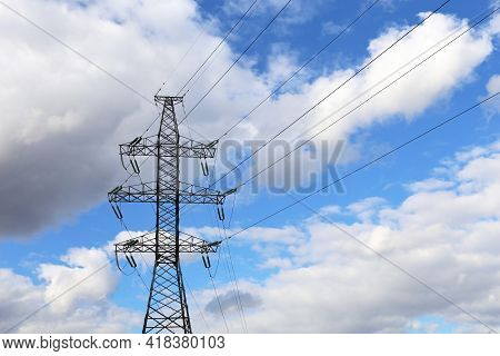 High Voltage Tower With Electrical Wires On Background Of Blue Sky With White Clouds. Electricity Tr