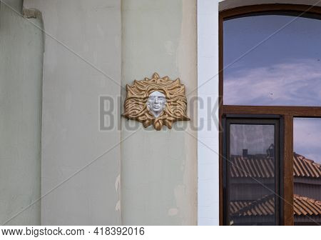 Bas-relief Female Face With Hair On The Wall Of The Facade Of An Ancient Building