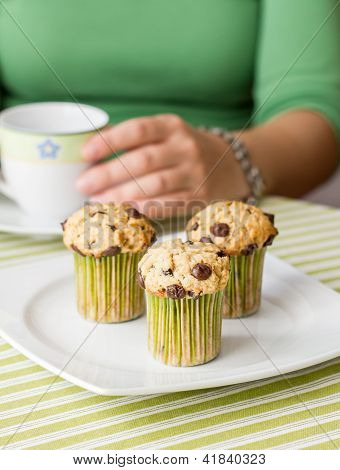 Flot pige med en kop og chokolade Chip Muffin til morgenmad