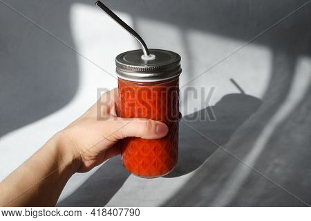 Female Hand Holding Glass Of Tomato Smoothie. Fresh-squeezed Tomato Juice With Pulp On Trendy Minima