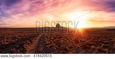 Striking Panoramic Landscape View Of A Dirt Road In The Dry Desert With A Mountain Peak In The Backg