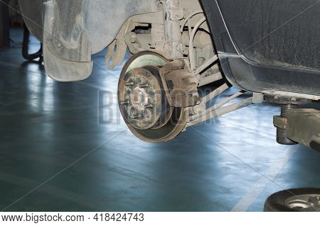A View Of A Rusty Brake Mechanism With The Rear Right Wheel Removed On A Car That Hangs On A Lift In