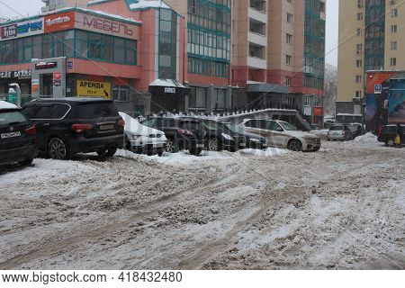 Russia, Novosibirsk 07.02.2021: Parked Cars Stuck In The Snow In The Winter In A Dirty City Uncollec