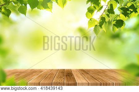 Empty Wooden Table On Blurred Green Background With Beautiful Fresh Leaves. Spring Or Summer Season.