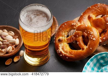 Lager beer mug, nuts, potato chips and fresh baked homemade pretzel with sea salt on stone table. Classic beer snack