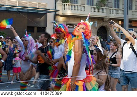Barcelona - Spain. June 29, 2019: Pretentious s in bright skirts and wigs painted in the color of the gay flag and horns from capricorn pose for the cameras at the parade