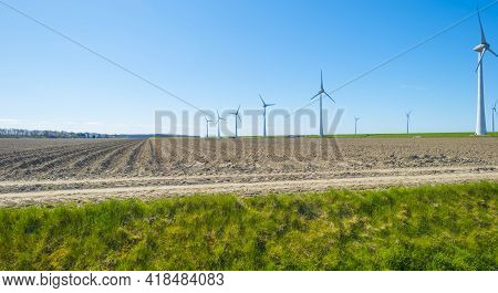 Wind Turbines For Renewable Energy In An Agricultural Field In Bright Blue Sunlight In Spring, Noord