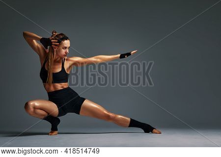 Beautiful And Athletic Girl In A Top And Shorts And Black Socks Posing In Studia On A Gray Backgroun