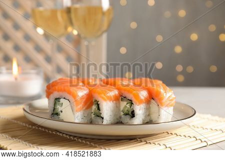 Tasty Sushi Rolls And Glasses Of Wine On Table Against Blurred Lights, Closeup