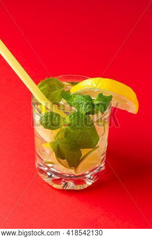 Citrus Water With Ice In A Glass Decorated With Lemon, Lime And Mint Slices And On Red Background. F