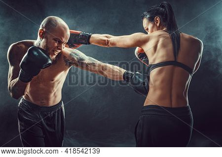 Shirtless Woman Exercising With Trainer At Boxing And Self Defen