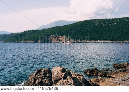 Two-masted White Yacht Sails On The Sea Along The Hilly Coast