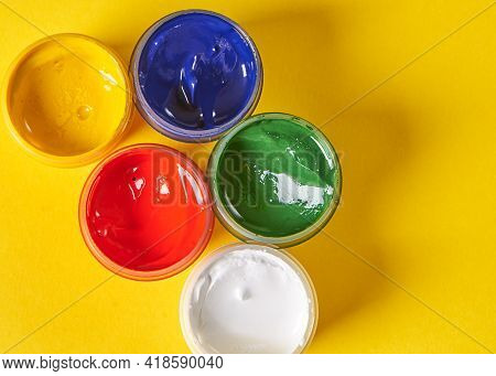 Five Colors Of Gouache Stands On A Yellow Background