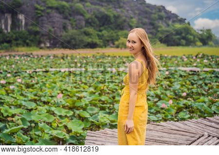 Young Woman In A Yellow Dress On The Path Among The Lotus Lake. Mua Cave, Ninh Binh, Vietnam. Vietna