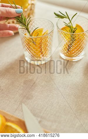 Female Hand Put Rosemary In Glasses, Making Fresh Lemonade
