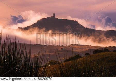 Rocca Di Radicofani Main Tower Fortification Covered With Morning Mist. Sunrise Light Covering The C