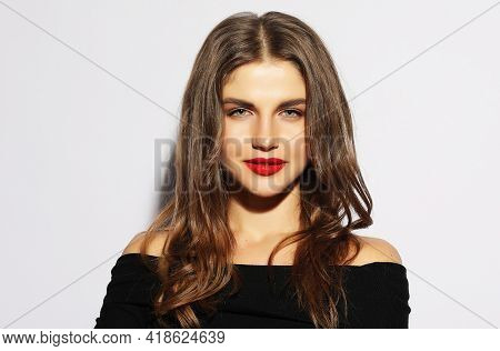 Blond woman in black dress posing with crossed arms and looking