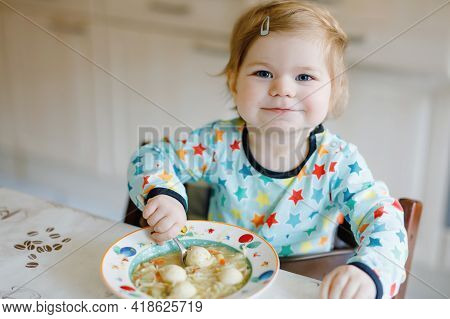 Adorable Baby Girl Eating From Spoon Vegetable Noodle Soup. Food, Child, Feeding And Development Con