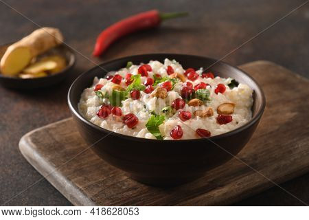 Curd Rice With Pomegranate, Cilantro, Mustard Seeds, Ginger On A Black Background. Indian Cuisine