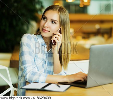 Business wooman using laptop at cafe. Young beautiful girl sitti