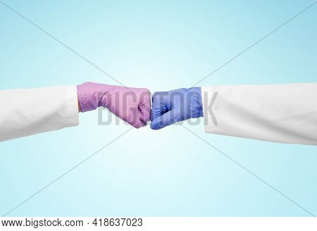 medicine, health protection and healthcare concept - hands of doctors in gloves make fist bump gesture over blue background