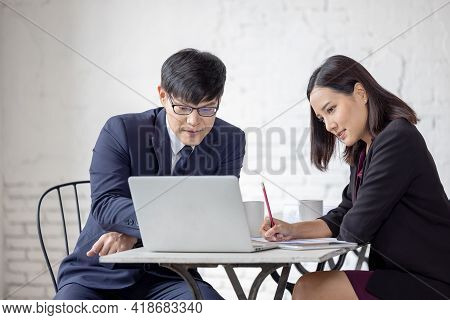 Business Man And Woman Sit At Ther Table Looking At Computer Laptop
