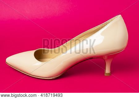 Classic Beige Patent Leather Shoe With Low Kitten Heel On Purple Background.