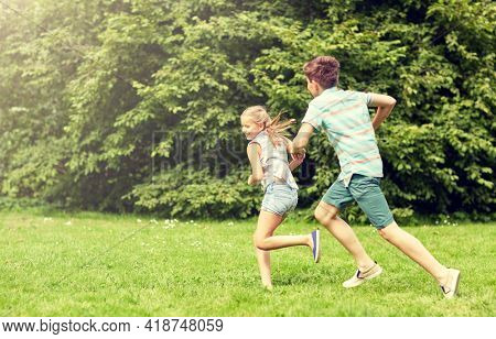 friendship, childhood, leisure and people concept - group of happy kids or friends playing catch-up game and running in summer park