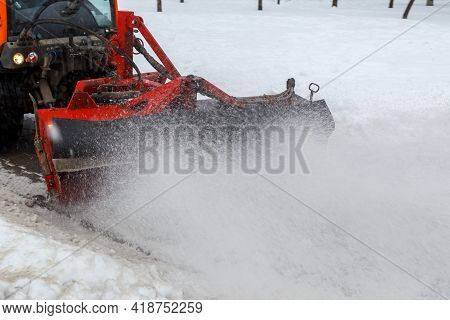 Snow Cleaning. Snow Removal Tractor Clearing Snow From Pavement With Special Round Spinning Brush,