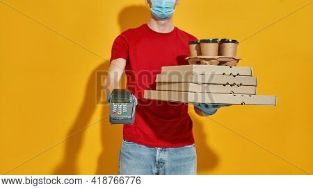 Paying Terminal, Pizza Boxes And Coffee Cups In Hands Of Young Caucasian Courier Wearing Rubber Glov