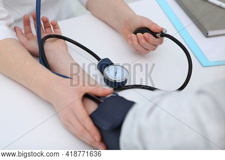 Doctor Checking Blood Pressure Of Woman In Clinic, Closeup