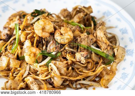 Close-up On Penang Char Kuey Teow Is Popular Fried Noodle With Coceral, Shrimp And Eggs In Black Sau