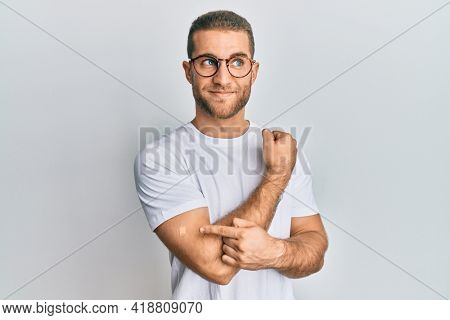 Young caucasian man wearing band aid for vaccine injection smiling looking to the side and staring away thinking. 