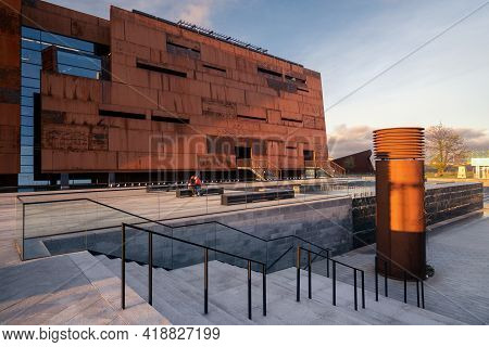 Gdansk, Poland - 06.05.2017: Young Couple On A Bench In Front Of Modern Industrial Building. Europea