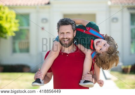 Father Giving Son Piggyback Ride After School Study. Parent And Pupil Of Primary School Schoolboy Wi