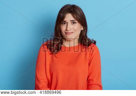 Young Beautiful Dark Haired Woman Frowning Face, Looking Directly At Camera, Wearing Orange Casual J