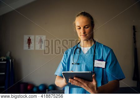Caucasian Nurse Preparing For Online Consultation With Sick Patient Using Digital Tablet Standing In