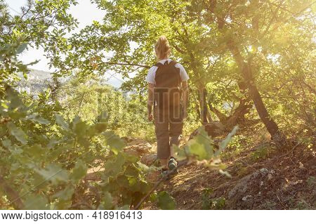 Young Woman Hiking With Backback Through Forest In Sunny Day.