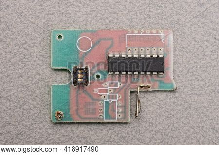 An Old Colored Plastic Microcircuit Board With Black Details Lies On A Gray Table